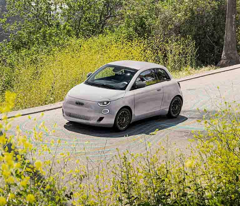 A raised angle of a 2024 Fiat 500e Inspired By Beauty being driven on a highway.